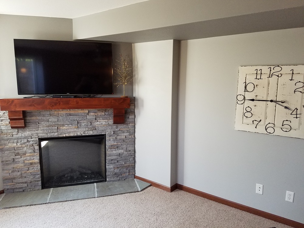 Corner fireplace in basement with electric insert.